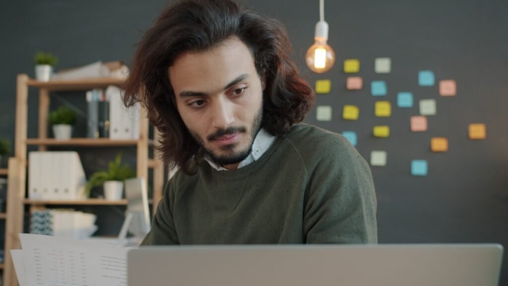 Person reviewing documents beside a laptop