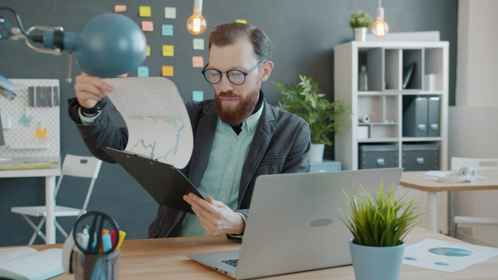 Person reviewing printed charts beside a computer