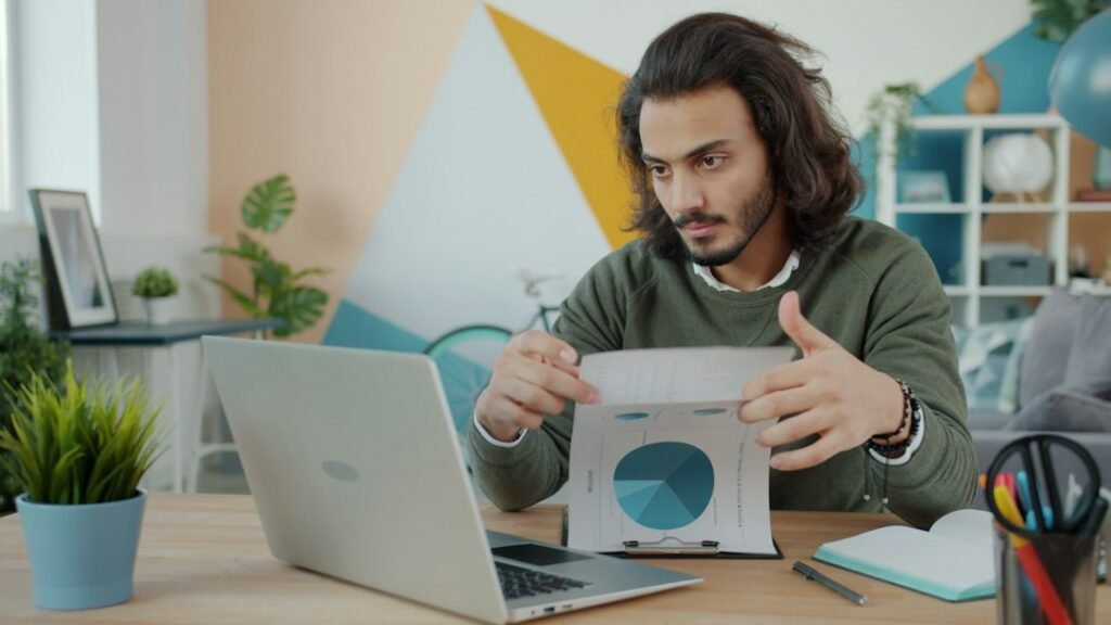 Person working with documents and a laptop at a desk